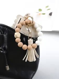 Close-up of beige silicone beaded keychain with PU leather cardholder on a black bag.