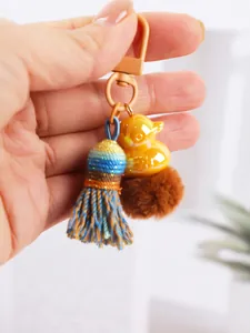 Detailed view of handmade woven tassel keychain with yellow duck charm and brown pom-pom