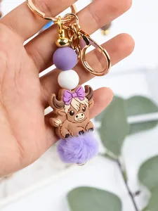 Detailed view of silicone bead keychain with cute highland cow charm and purple pom-pom