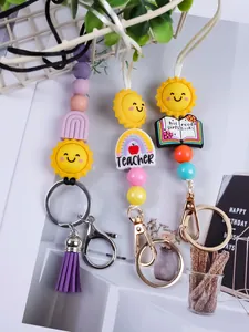 Macro view of beaded keychains featuring cartoon suns and Teacher themed silicone charms.
