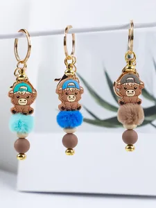 Detail view of silicone bead keychains with fluffy fur balls and cartoon cow charms