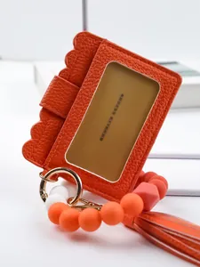 Close-up of orange PU leather card holder with silicone beaded wristlet and tassel