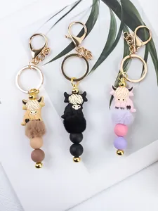 Detail view of cartoon highland cow keychains with silicone beads and fur pom-poms