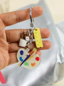 Detalle de llavero creativo de acrílico con paleta de pintura y dije de regla