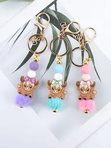 Detail view of cartoon highland cow keychains with silicone beads and faux fur pom-poms