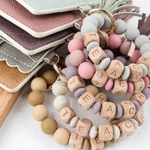 Detailed view of silicone bead bracelet with wooden TEACH blocks and leather card holder