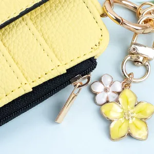Nahaufnahme des gelben Leder-Kartenhalters mit eleganten Blumenanhängern aus Legierung