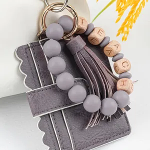 Detail of purple PU leather card holder with "TEACH" beaded tassel wristlet keychain