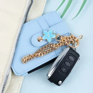 Detailaufnahme eines hellblauen Leder-Kartenhalters mit legiertem Blumenanhänger und Reißverschluss