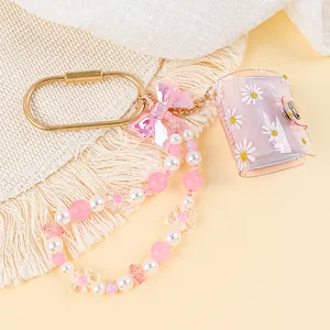Close-up detail of mini daisy photo album keychain with pink beaded bracelet and bow charm.