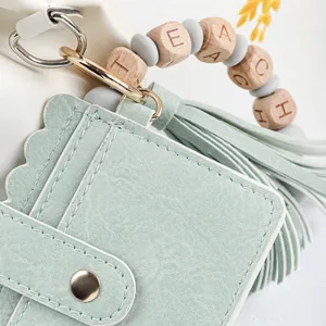 Detail of mint green leather card holder with TEACH beaded wristlet and tassel.