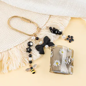 Detailed view of mini photo album keychain with acrylic beads and daisy patterns.