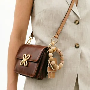Close-up view of brown PU leather bag with beaded letter keychain and gold clasp