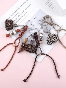 Set of leopard print mini bag charms with heart keychains and braided ropes on pink.