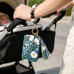 Detailansicht eines Kartenhalters mit Gänseblümchen-Druck und Perlenarmband am Handgelenk