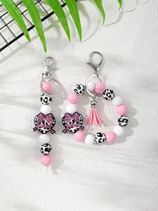 Detalle de llavero de cuentas de silicona con estampado de vaca y dije de corazón MAMA.