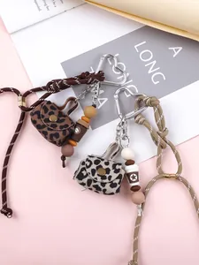 Close-up of leopard print mini bag keychains with beaded charms and heart carabiners.