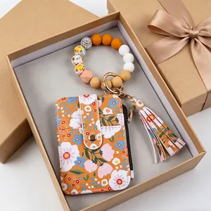 Nahaufnahme eines floralen Leder-Kartenhalters mit Perlen-Armband in einer Geschenkbox