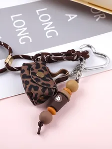 Close-up detail of leopard print mini purse keychain with braided cord and beaded accents
