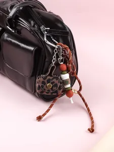 Close-up of leopard print coin purse keychain with coffee cup charm and braided rope
