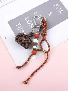 Detailed view of a leopard print mini bag keychain with braided rope and coffee charm