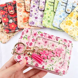 Zoom sur un porte-cartes à fleurs roses avec pompon et pendentif fleur décoratif.