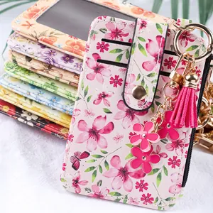 Vue détaillée d'un porte-cartes à imprimé floral rose avec pompon et breloques de fleurs