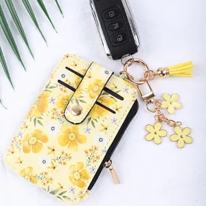 Porte-cartes élégant à imprimé floral jaune avec fermeture éclair et pompon fleuri.