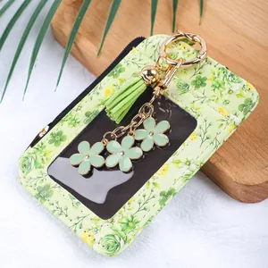 Détail d'un porte-cartes floral vert clair avec pompon et breloques fleurs