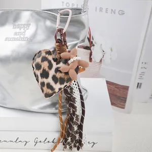 Detail eines Taschenanhängers mit Herz aus Leopardenmuster, Ballonhund und Spitze.