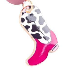 Κοντινό πλάνο ενός ροζ σμάλτου γούρι μπότα cowgirl με λεπτομέρεια εκτύπωσης αγελάδας