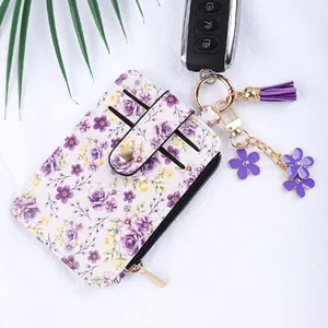 Gros plan sur un porte-cartes à motif floral avec zip et porte-clés à pompon violet chic