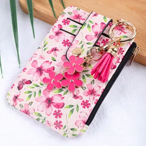 Détail du porte-cartes à imprimé floral rose avec porte-clés à pompons et fleurs