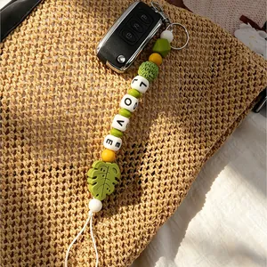 Handgemaakte siliconen kralen sleutelhanger met LOVE-letters en groene bladhanger detail.