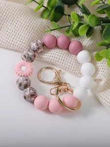 Close-up of a pink silicone daisy bead keychain bracelet with gold-tone lobster clasp