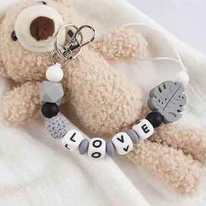 Detailopname van een siliconen kralen sleutelhanger met 'LOVE'-blokjes en bladhanger
