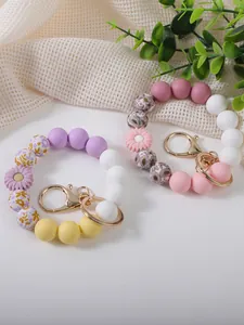Close-up of colorful silicone beaded wristlet keychains with daisy charms and floral beads.
