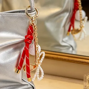 Primer plano de un colgante de bolso de golf con cuerda roja y lazo de perlas en bolso plata