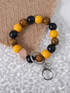Colorful wooden bead keychain bracelet with yellow and black accents on burlap texture.