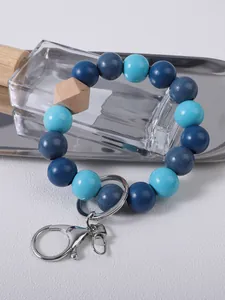 Close-up of blue wooden bead bracelet keychain with silver lobster clasp on white tray.