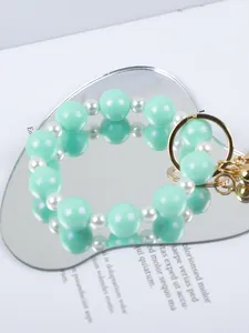 Macro detail of mint green silicone beads and white pearls on a heart mirror.