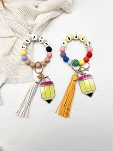 Detalle de llaveros de pulsera de cuentas de silicona con letras TEACH y lápiz colgante