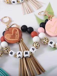 Detailopname van handgemaakte kralen sleutelhanger met mama gravure en kwastje