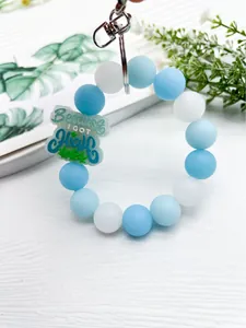 Vista detallada de llavero de cuentas de silicona azul y blanco con amuleto