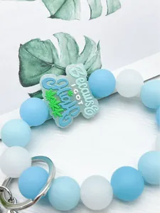 Detalle del llavero de cuentas de silicona azul y blanco con placa decorativa.