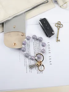 Detailed view of purple silicone bead wristlet keychain with grey tassel and gold ring