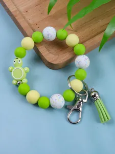 Close-up of a green turtle silicone bead keychain wristlet with a matching tassel.