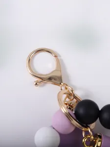 Detailopname van de gouden kreeftensluiting en matte siliconen kralen op de sleutelhanger
