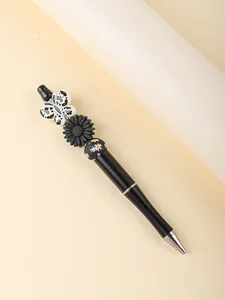 Detail view of a black ballpoint pen featuring decorative butterfly and flower beads