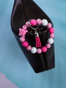 Close-up of pink silicone beaded keychain with turtle charm and tassel on a bag